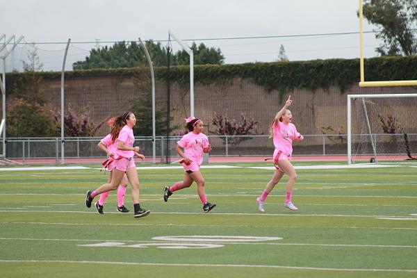 Juniors Emi Kong, Brooklyn Sylve and Olivia Weeks cheer as they run off the field for the half-time show.