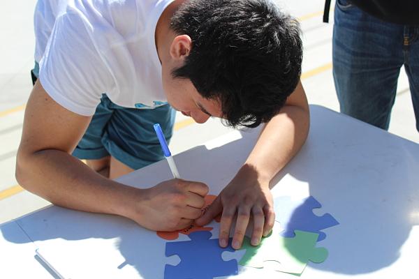 Seniors Prashid Pokharel write on puzzle pieces at the fwd:love table in the quad during lunch.