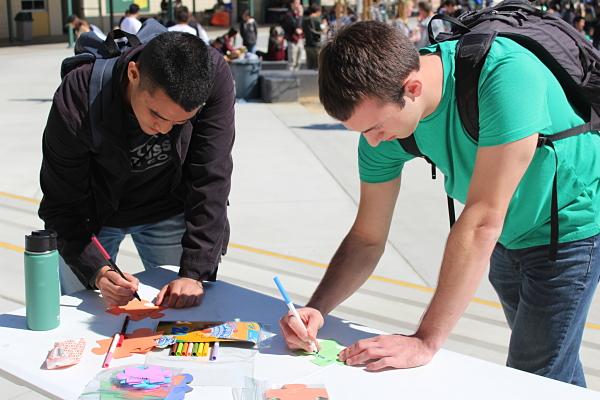  (from left) Seniors Kenta Asai, Prashid Pokharel and Cameron Schindler write on puzzle pieces at the fwd:love table in the quad during lunch.
