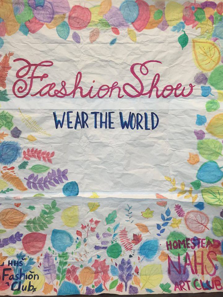 Fashion Show’s “Wear the World” poster designed by NAHS was displayed on the cafeteria wall for attendees to use as a photo backdrop.