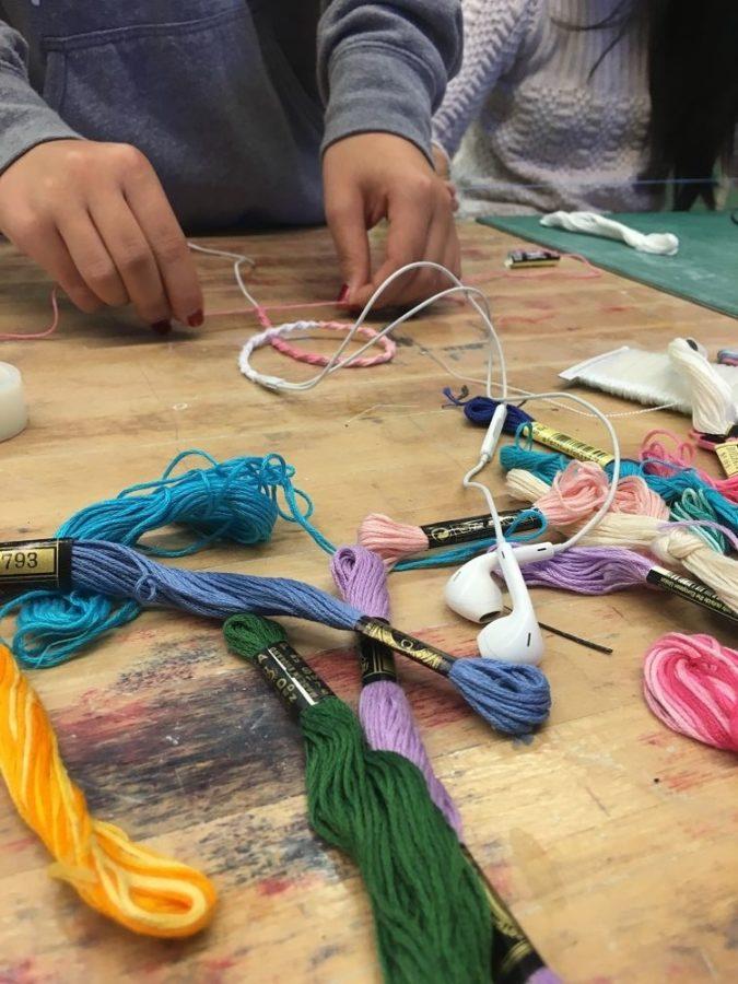 An art club officer using embroidery thread to decorate her headphones.