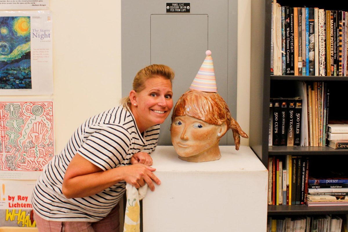 Ceramics teacher Jodi Johnson poses with her ceramic sculpture.