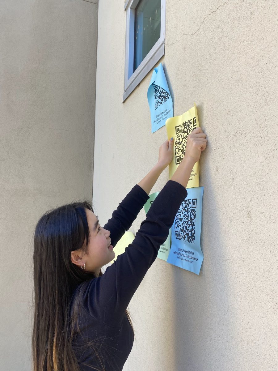 EL commissioner Thien-Mai Vu hangs up winter formal posters to promote the dance around the school.