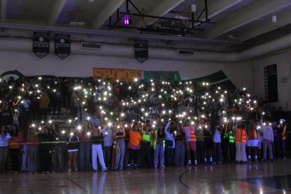 Students wave their phone flashlights as they chant at the rally.