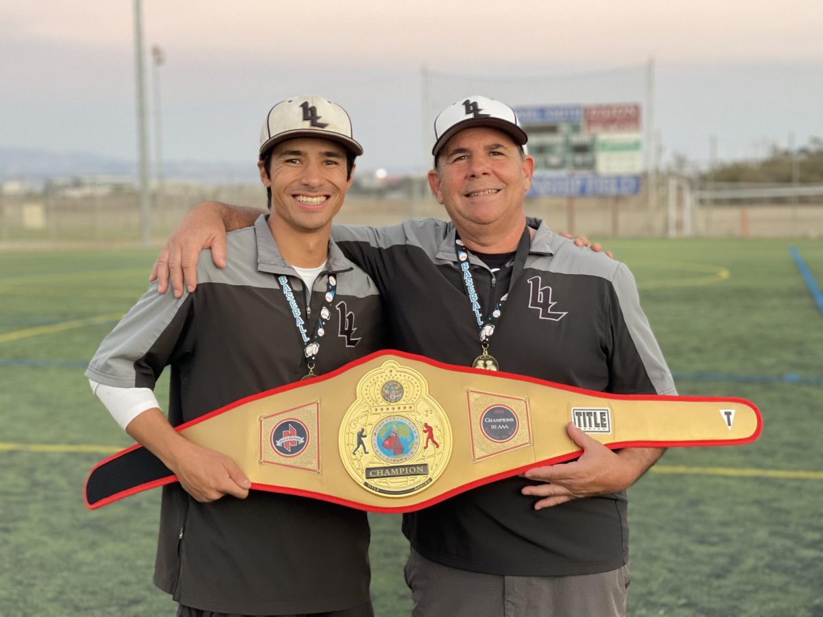 Curtis Currier (left) and his father, JV coach Craig Currier (right), pose with a travel ball tournament trophy.